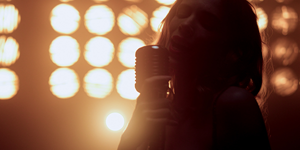 Silhouette of singer with bright stage lights in the background