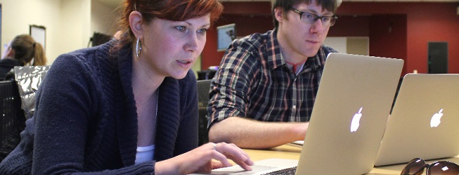 A man and a woman studying together on laptops.