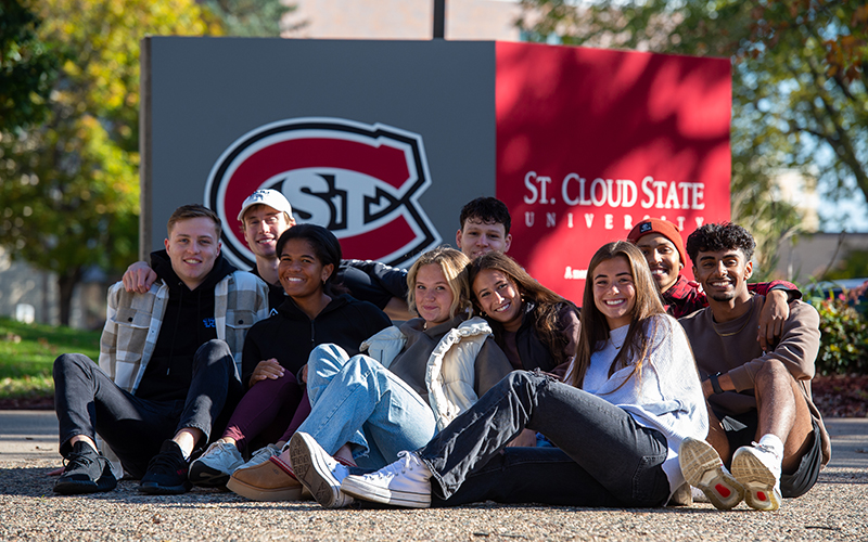 Group of students sitting in front of SCSU sign