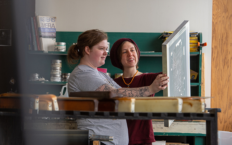 Student looking at artwork with teacher