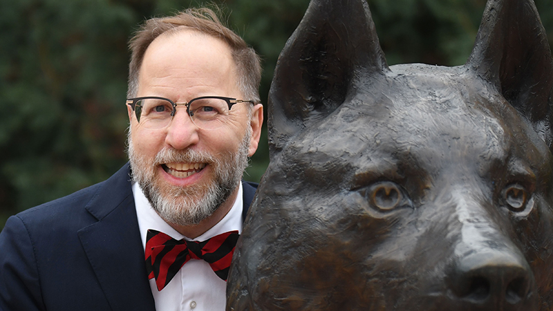 President Tomso smiling with the SCSU bronze husky statue