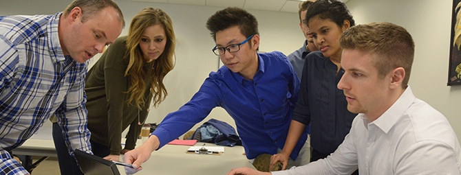 St. Cloud State psychology students interact in class while looking at a computer.