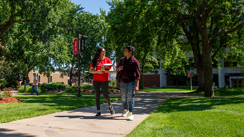 Two students walking on sidewalk.