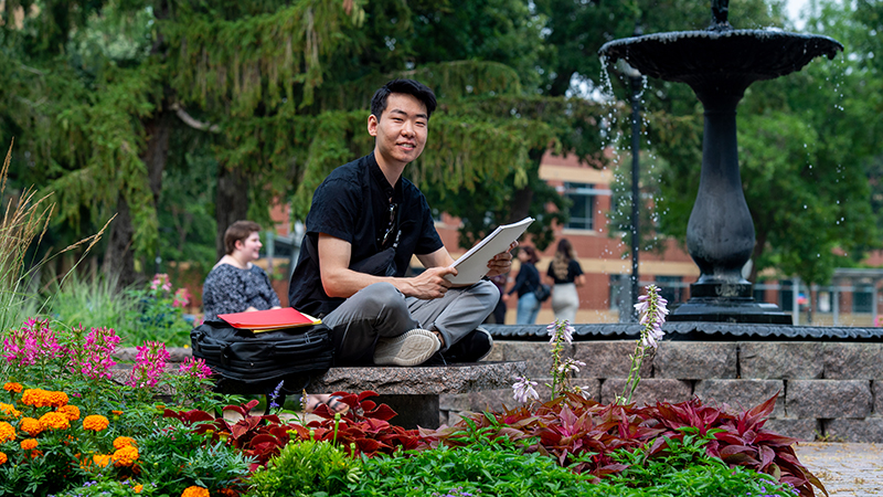 Student seated in outdoor park doing homework