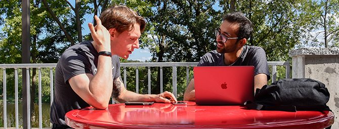 Two students talk at a table