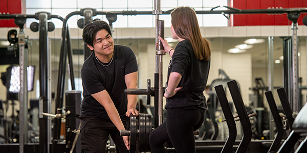 Two students load weights on equipment at the SCSU Campus Recreation weight room