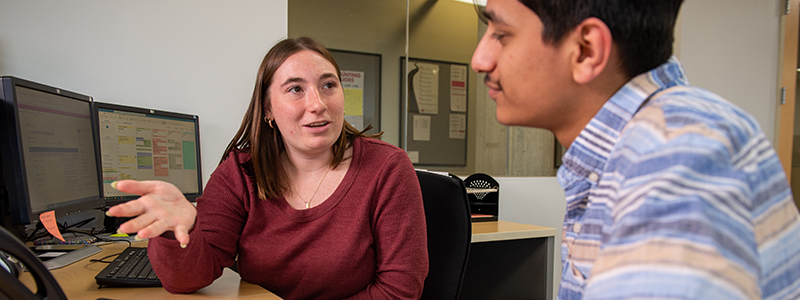 A student and advisor meet with one another at a desk