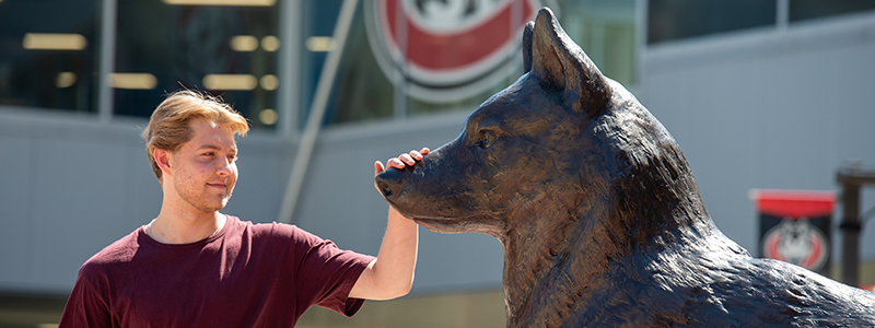 A student rubs the nose of the Husky statue for good luck