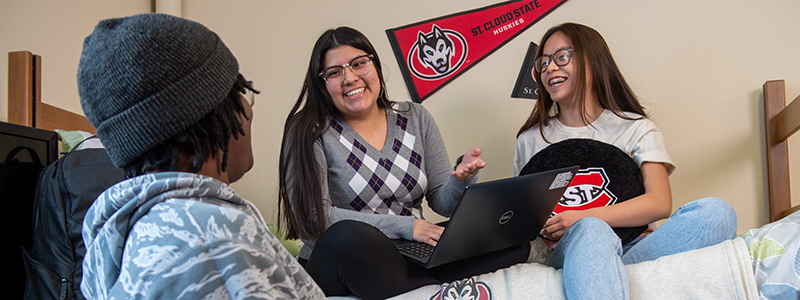 Three students hang out in a SCSU dorm room