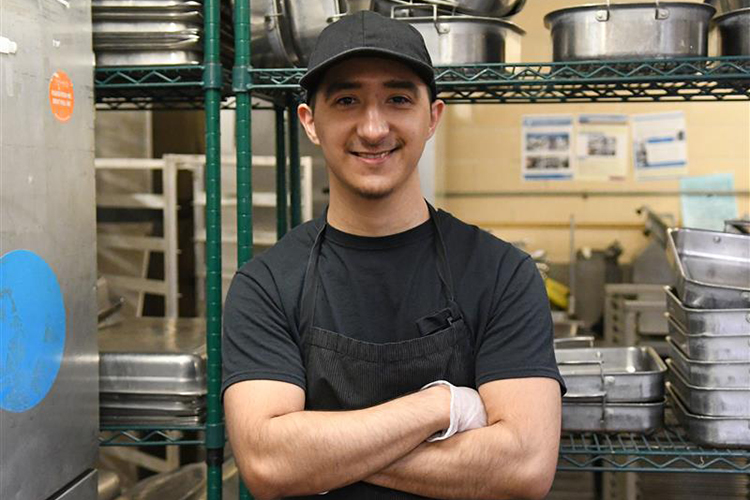 Young man stands proudly in commercial kitchen