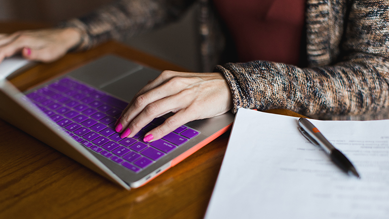 Purple laptop with hands typing