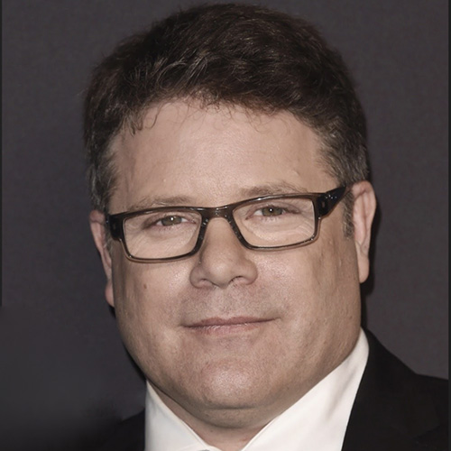 Sean Astin is pictured in a black suit and tie