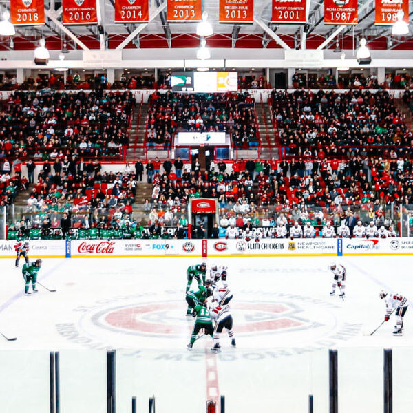 SCSU and North Dakota hockey teams face off with a large crowd of fans visible in the background