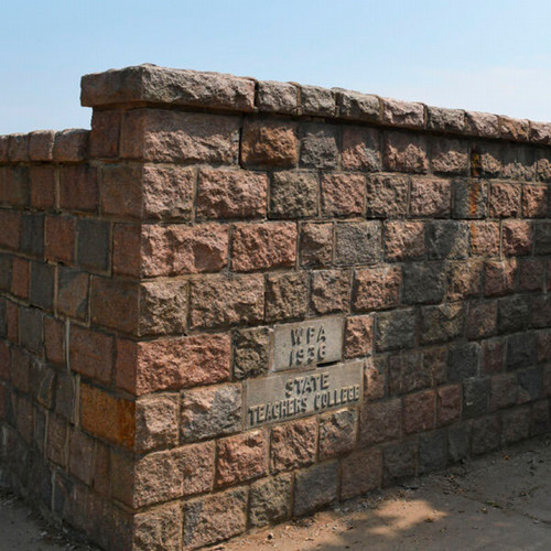 A large granite wall with the words WPA 1936 and State Teachers College in bricks 