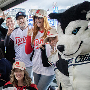President Tomso and alumni pose for a photo at a Twins game
