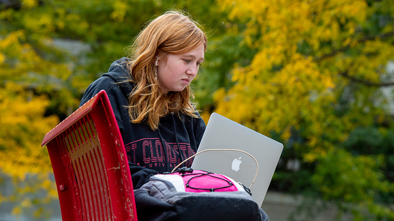 Student on bench with laptop