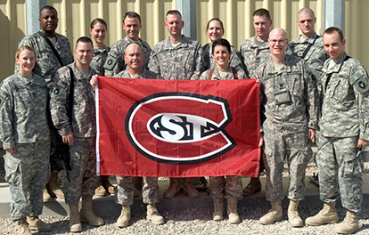 Military personnel holding the St. Cloud Stat flag