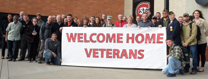Veterans holding poster with Welcome home veterans written on it.